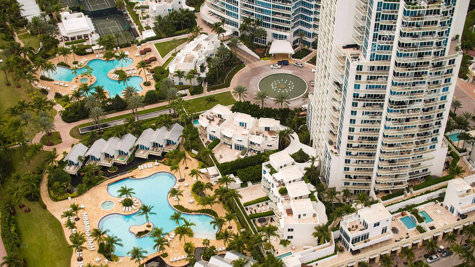 Aerial view of resort-style pool decks, villas, and the arrival court at Continuum on South Beach, Miami Beach, Florida, highlighting luxury and ultra luxury condos with lush tropical landscaping and multiple curving pools.