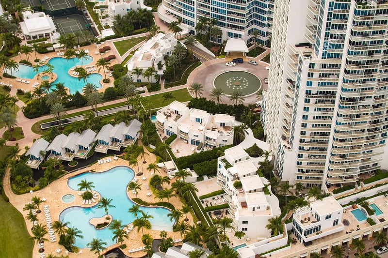 Aerial view of resort-style pool decks, villas, and the arrival court at Continuum on South Beach, Miami Beach, Florida, highlighting luxury and ultra luxury condos with lush tropical landscaping and multiple curving pools.