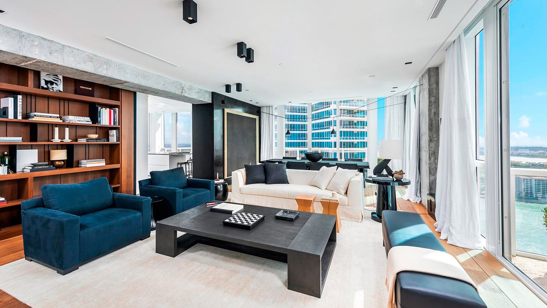 Corner living room at Continuum on South Beach, Miami Beach, Florida, within luxury and ultra luxury condos, featuring built-in bookshelves, modern seating, floor-to-ceiling glass, and water views.