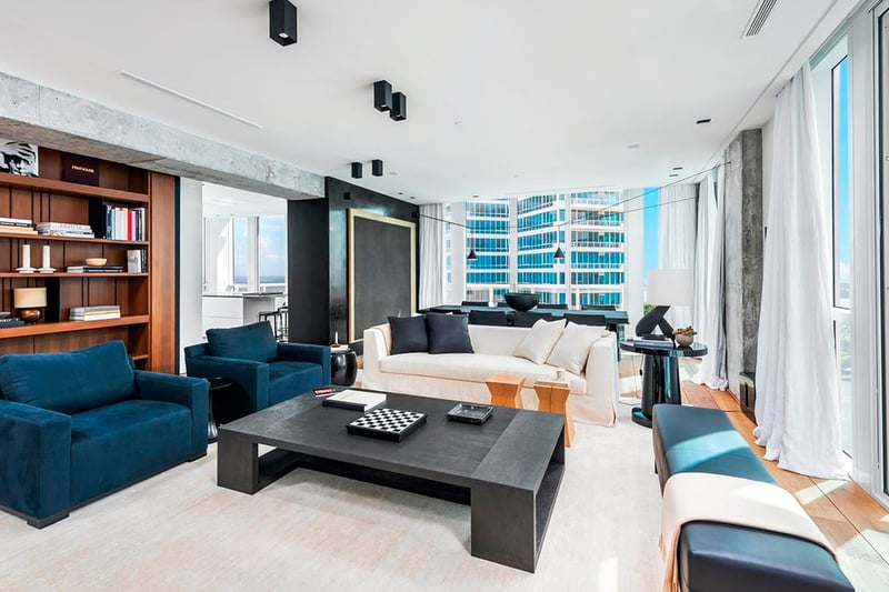 Corner living room at Continuum on South Beach, Miami Beach, Florida, within luxury and ultra luxury condos, featuring built-in bookshelves, modern seating, floor-to-ceiling glass, and water views.
