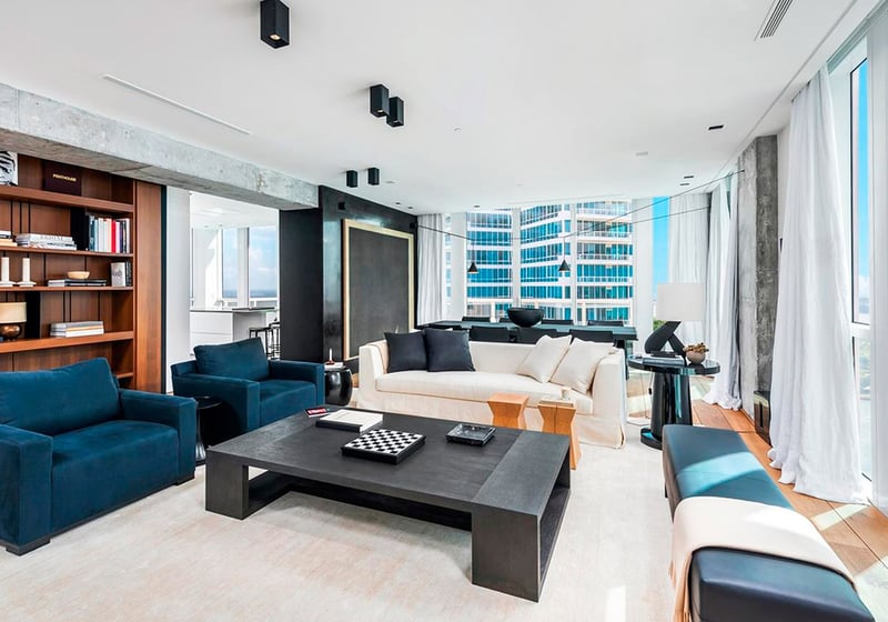 Corner living room at Continuum on South Beach, Miami Beach, Florida, within luxury and ultra luxury condos, featuring built-in bookshelves, modern seating, floor-to-ceiling glass, and water views.