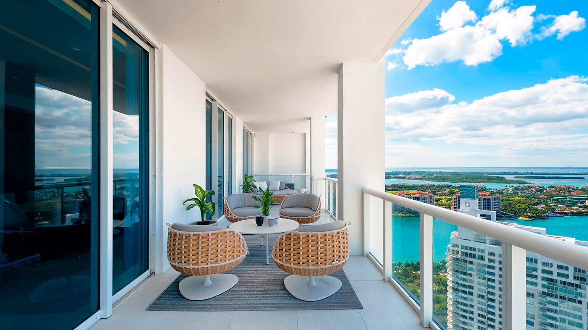 Covered balcony lounge at Continuum on South Beach, Miami Beach, Florida, extending luxury and ultra luxury condos outdoors with woven chairs, a seating area, and wide bay views.