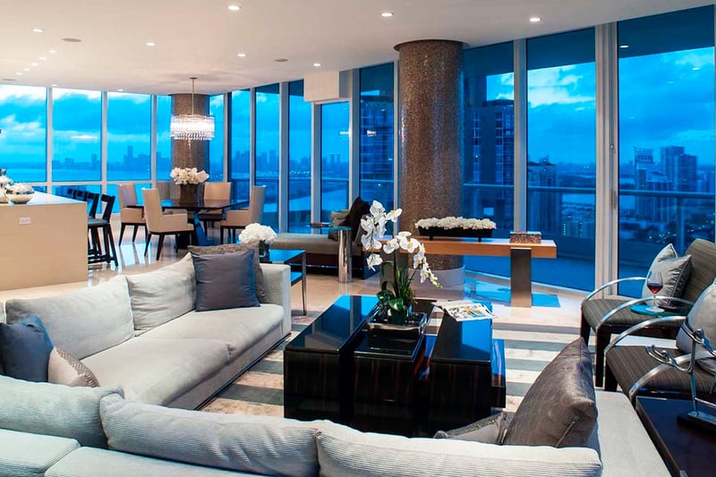 Open-plan living and dining area at Continuum on South Beach, Miami Beach, Florida, presenting luxury and ultra luxury condos with floor-to-ceiling glass, a modern kitchen, and an evening skyline view.