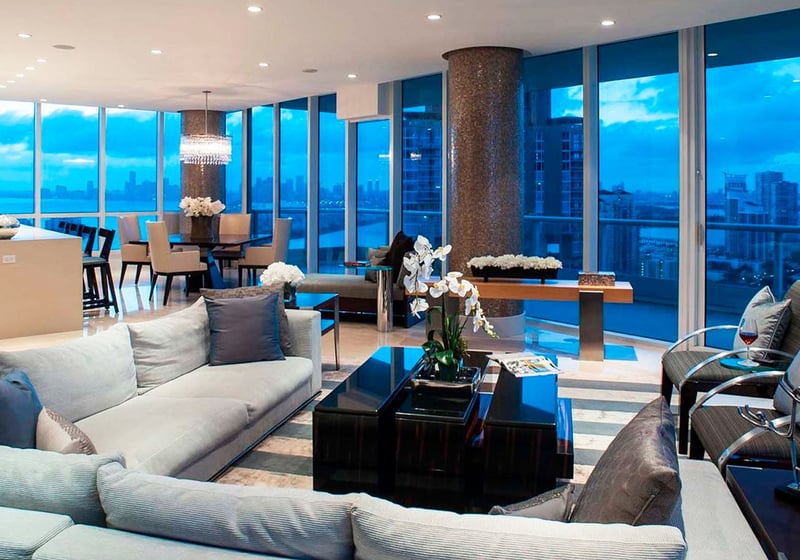 Open-plan living and dining area at Continuum on South Beach, Miami Beach, Florida, presenting luxury and ultra luxury condos with floor-to-ceiling glass, a modern kitchen, and an evening skyline view.
