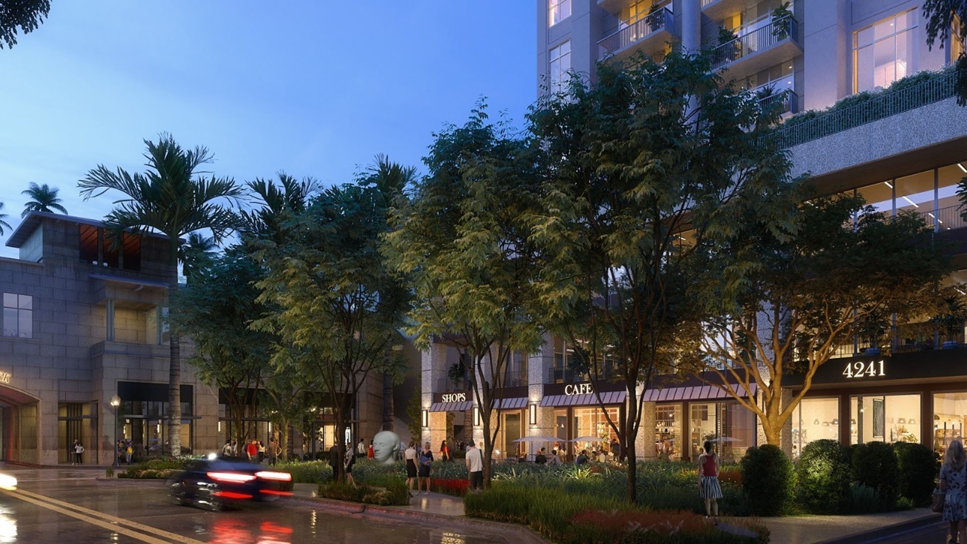 Twilight retail courtyard at Cora Merrick Park in Coral Gables with glowing storefronts, mature trees, and passing cars beneath luxury and ultra luxury condos.