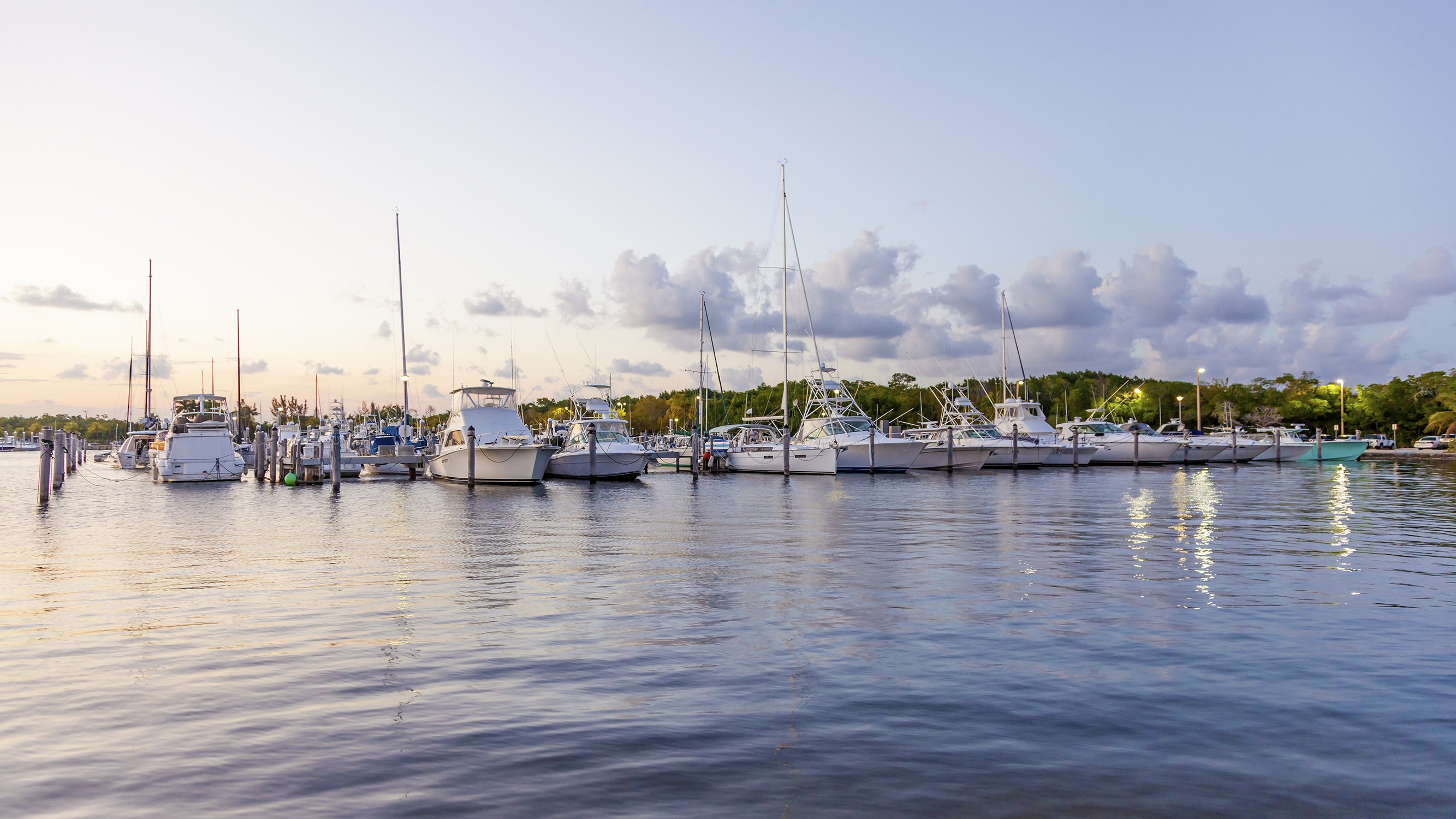 Coral Gables marina at sunset with boats and glowing sky, sought‑after waterfront locale for luxury and ultra luxury condos; preconstruction and resale inventory.