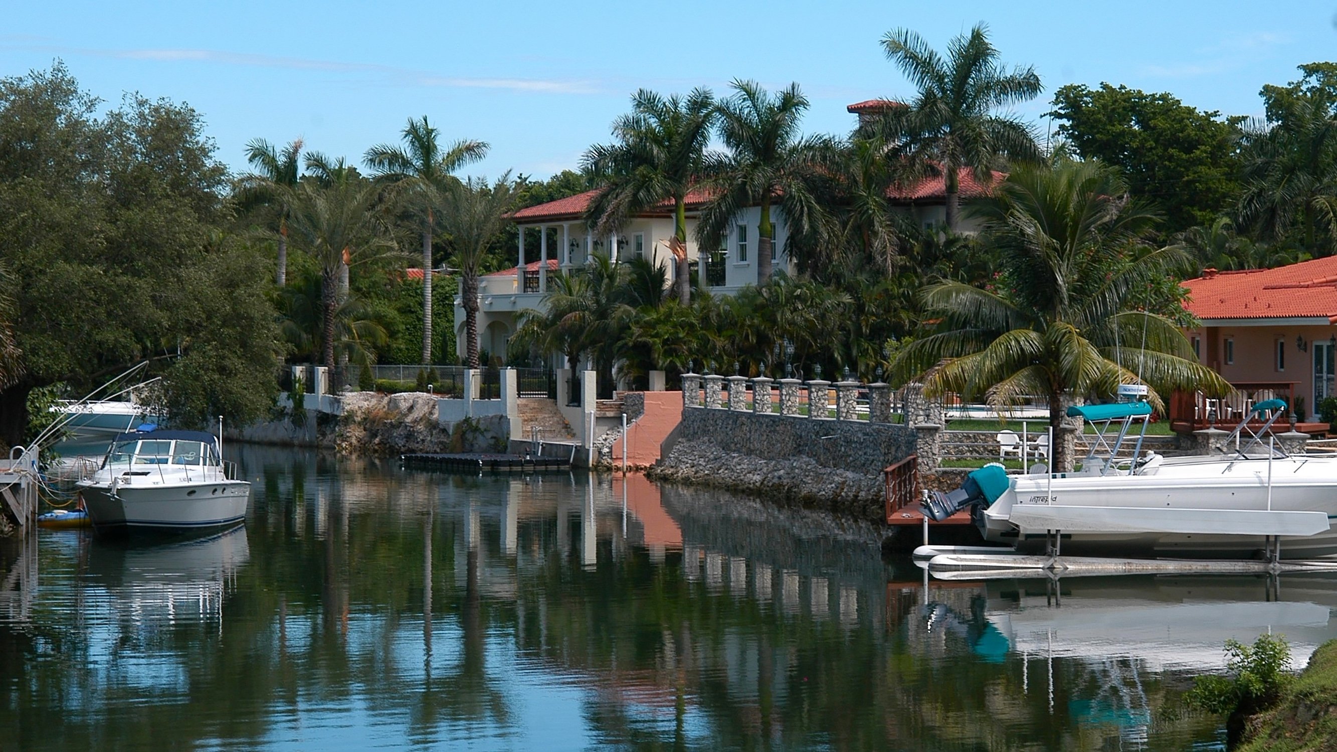 Coral Gables waterfront homes with boats and palm trees—prestigious shoreline close to luxury and ultra luxury condos, with preconstruction and resale.