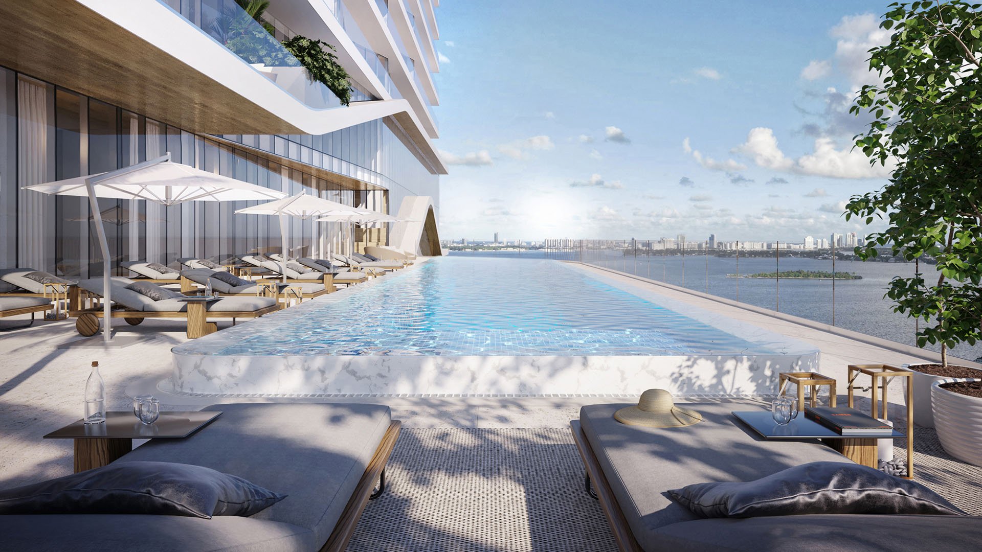 Cove Miami in Miami presents luxury and ultra luxury condos in preconstruction, featuring an infinity-edge pool deck with daybeds, umbrellas, and open water views stretching to the skyline.