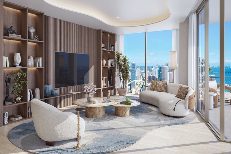 Great room at Delano Residences & Hotel, Miami, with a curved sofa, built-in shelving, floor-to-ceiling glass, and balcony bay views, showing luxury and ultra luxury preconstruction condos.