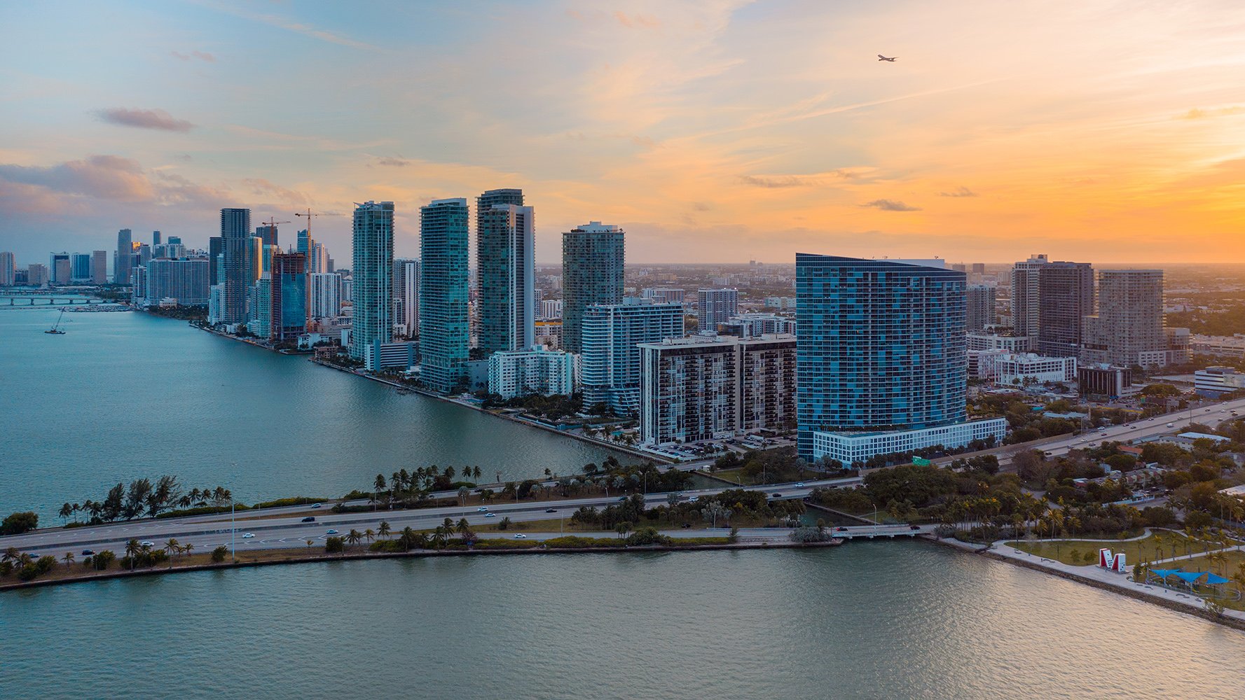 Edgewater, Miami sunset skyline over Biscayne Bay—golden light on waterfront towers; leading market for luxury and ultra luxury condos, with preconstruction and resale.