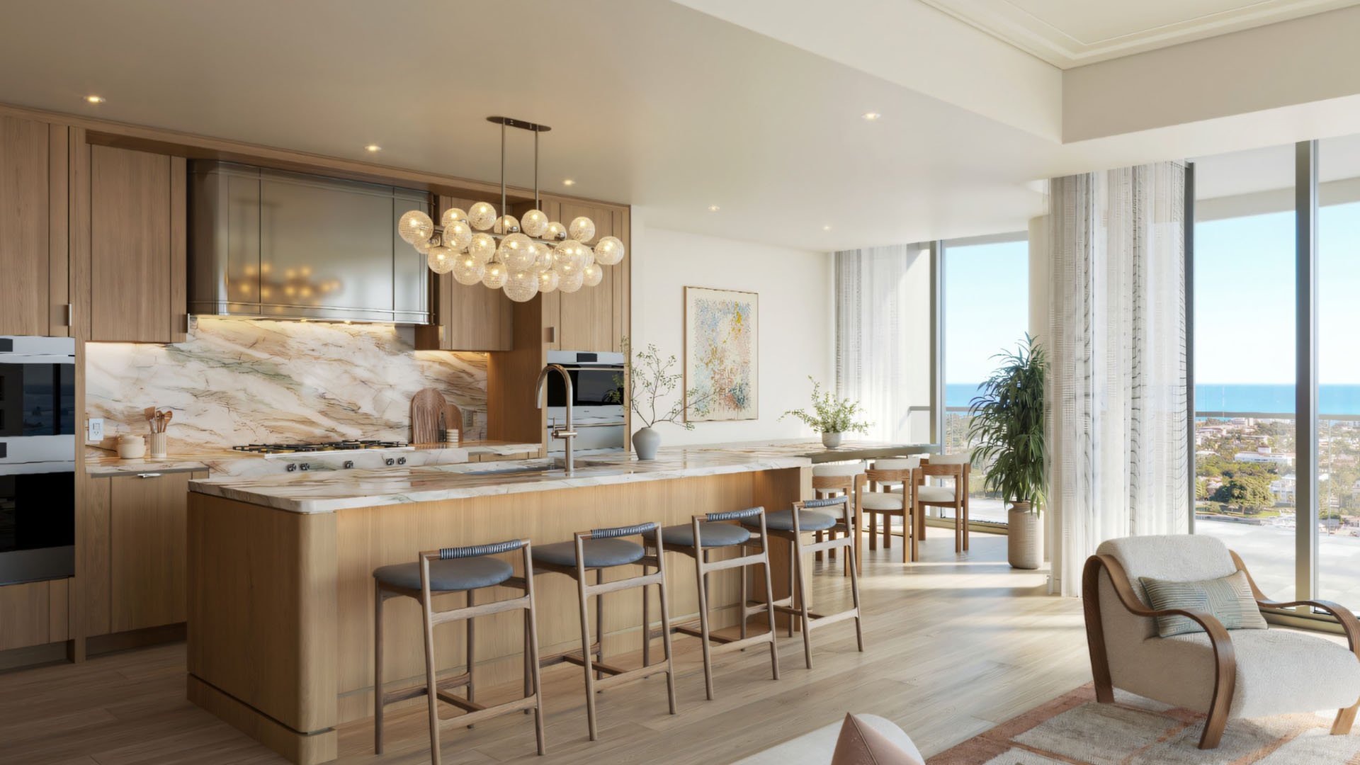 Edgeworth West Palm Beach luxury ultra luxury condos chef kitchen with a large marble island, warm wood cabinetry, pendant lighting, and open-plan dining space beside expansive windows with water views.