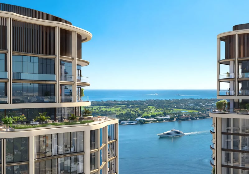 Edgeworth West Palm Beach luxury ultra luxury condos waterfront view framed between two curved towers, with expansive glass balconies, the Intracoastal waterway, and a yacht moving through the channel.