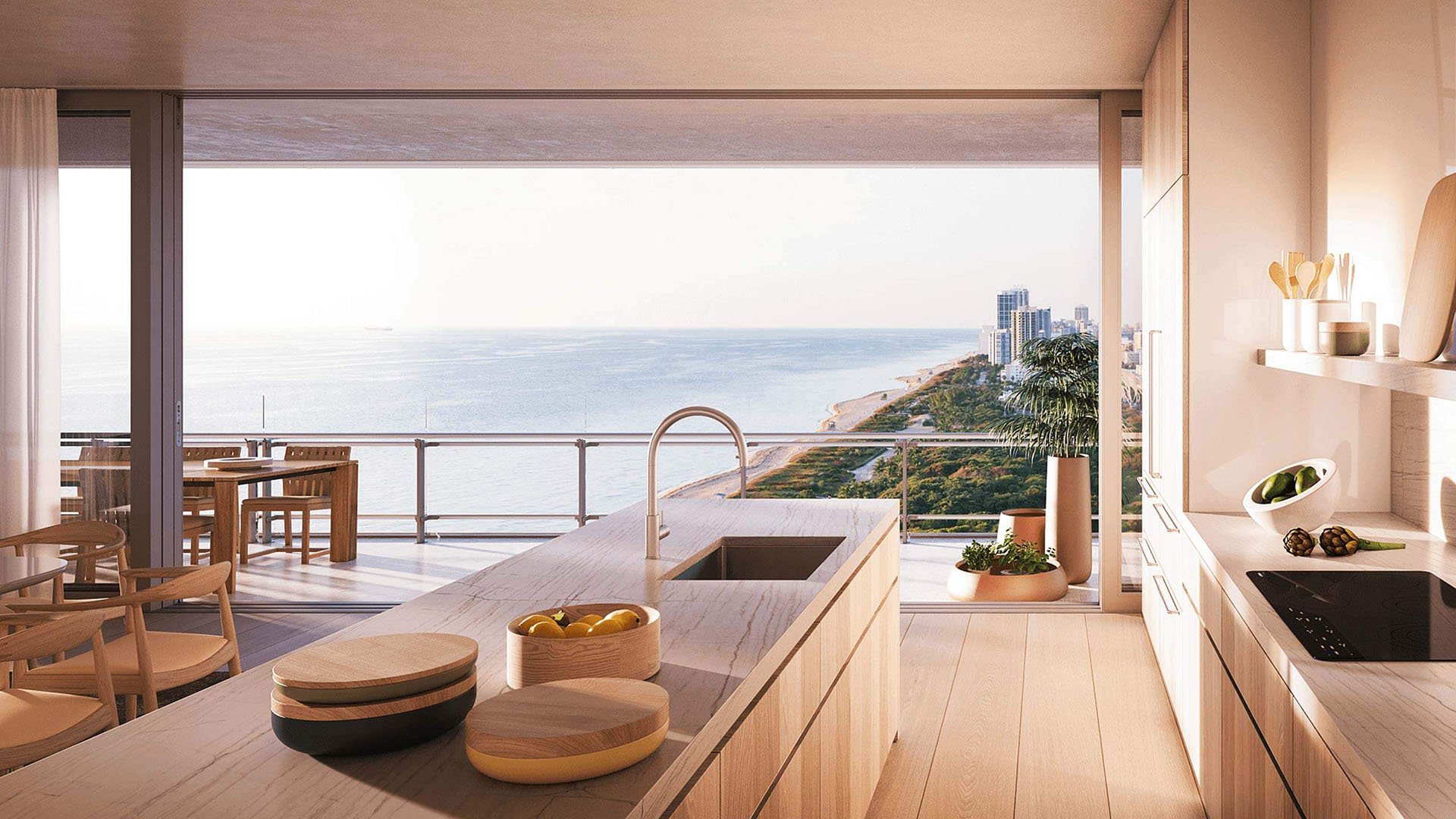 Eighty Seven Park, Miami Beach luxury and ultra luxury condos chef kitchen with a long island, integrated sink, warm wood cabinetry, and an oceanfront terrace view beyond.