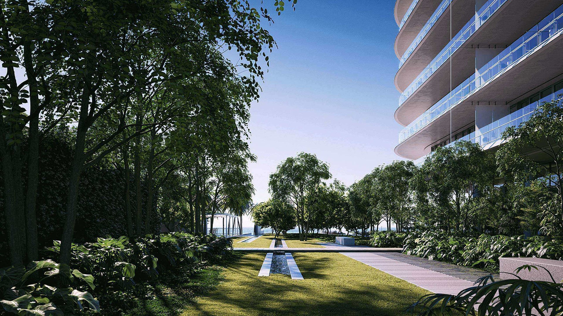 Eighty Seven Park, Miami Beach luxury and ultra luxury condos landscaped garden walkway with reflecting water channels, mature trees, and the curved residential facade to the side.