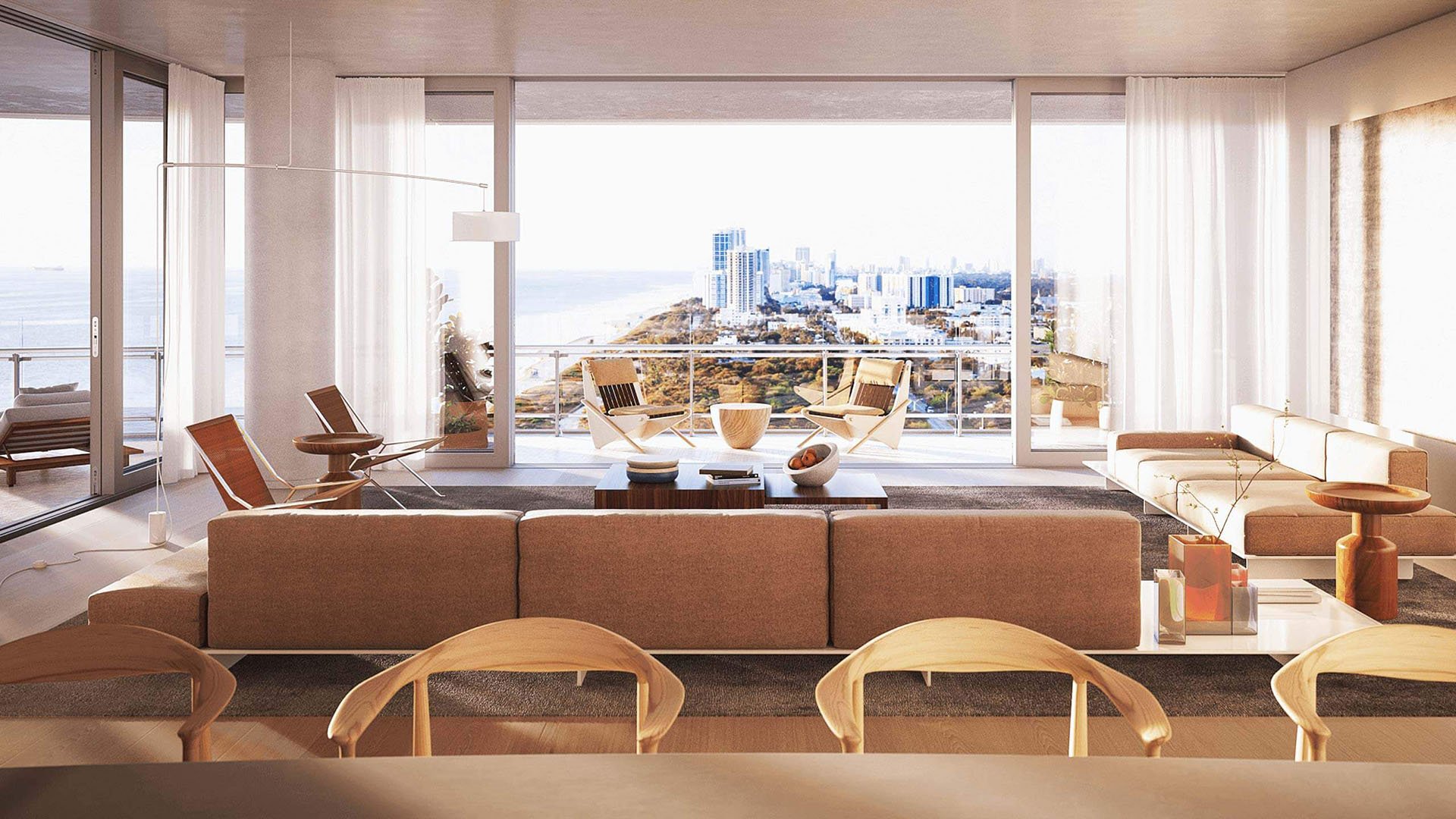 Eighty Seven Park, Miami Beach luxury and ultra luxury condos living room with a wall of glass, terrace seating, and a bright coastline and skyline view beyond the sofa.