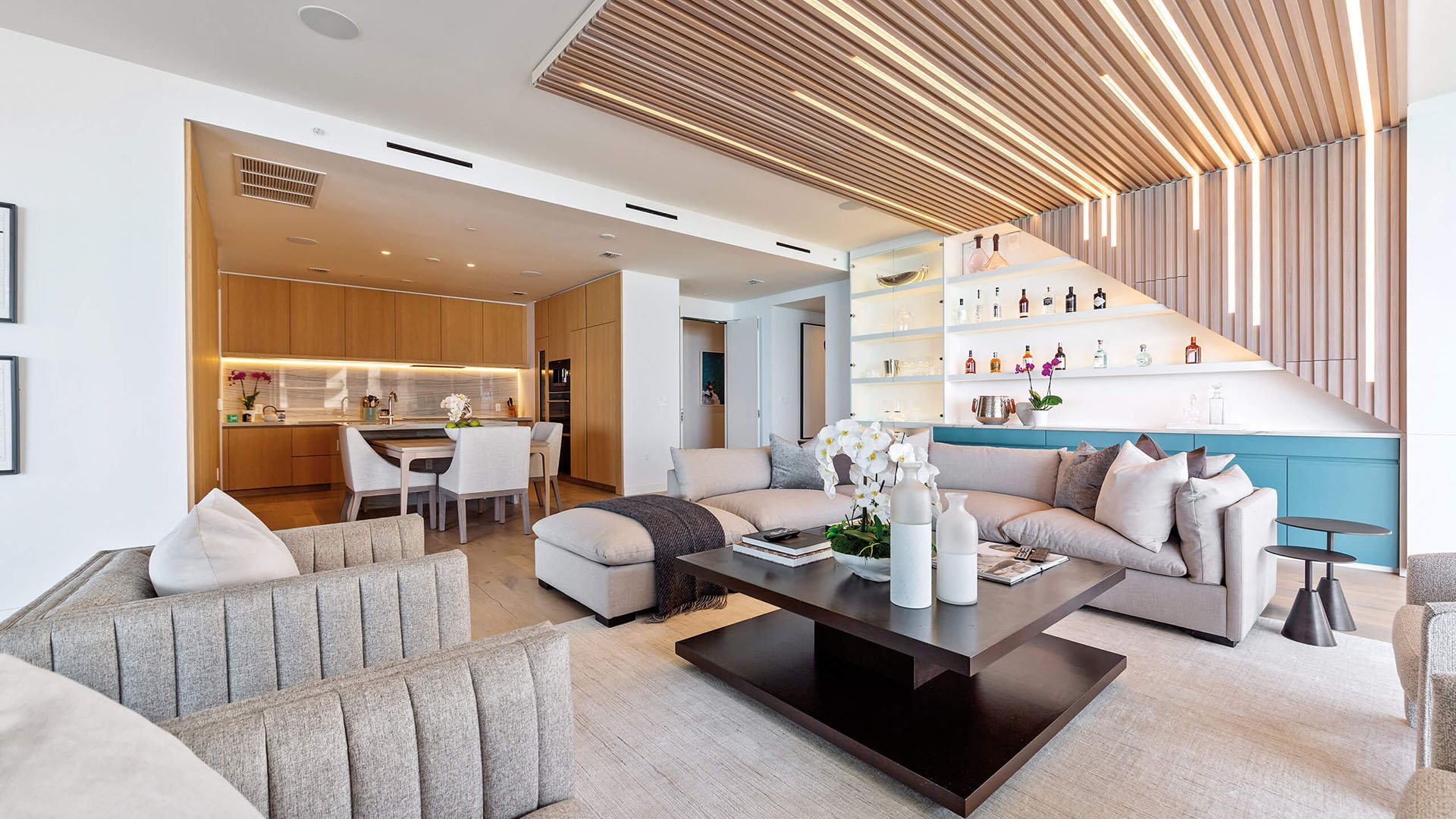 Eighty Seven Park, Miami Beach luxury and ultra luxury condos living room with a chef kitchen, sculptural ceiling detail, built-in display bar, and contemporary seating.