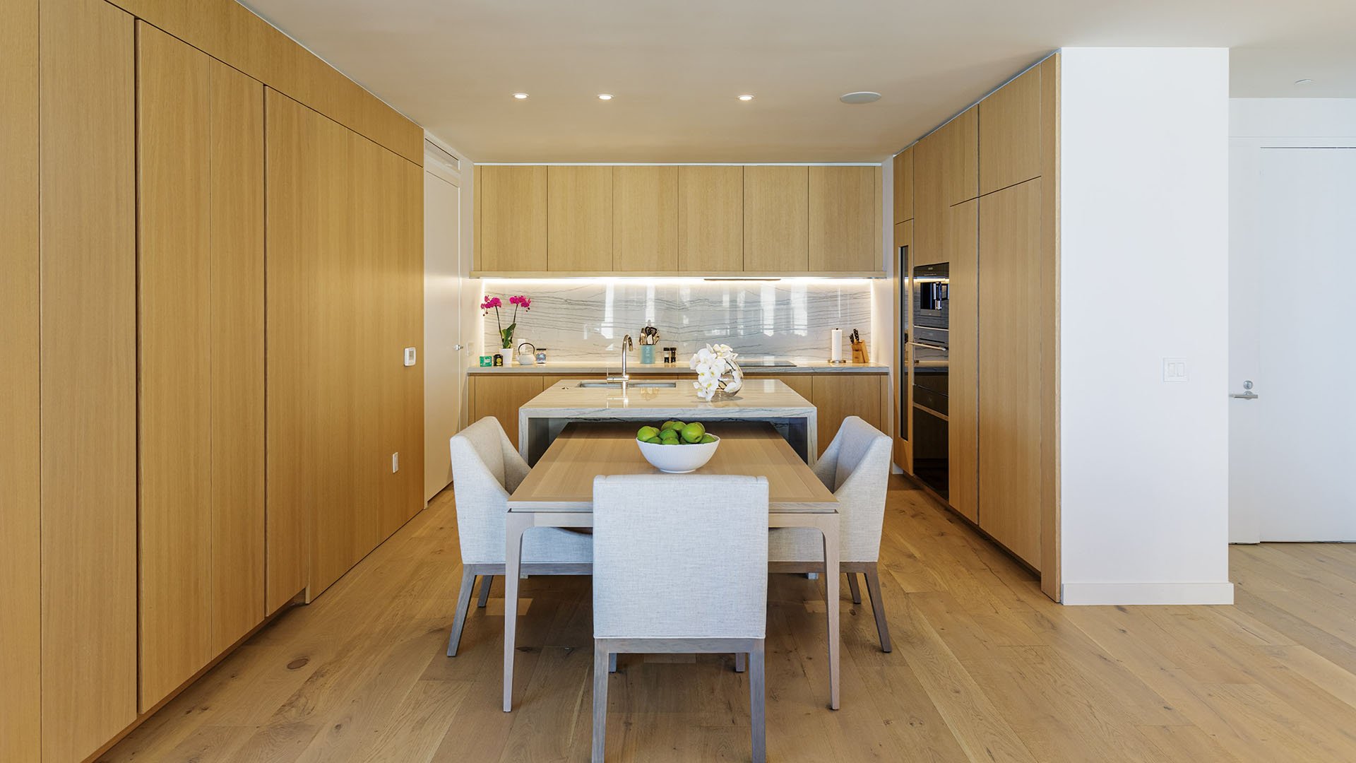 Eighty Seven Park, Miami Beach luxury and ultra luxury condos wood-paneled chef kitchen with integrated dining, full-height cabinetry, and a compact marble island.