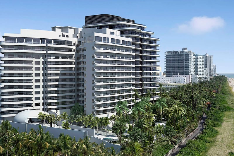 Aerial beachfront view of Faena House in Miami Beach, luxury and ultra luxury condos with a sculptural tower, palm-lined grounds, neighboring buildings, and the Atlantic shoreline.