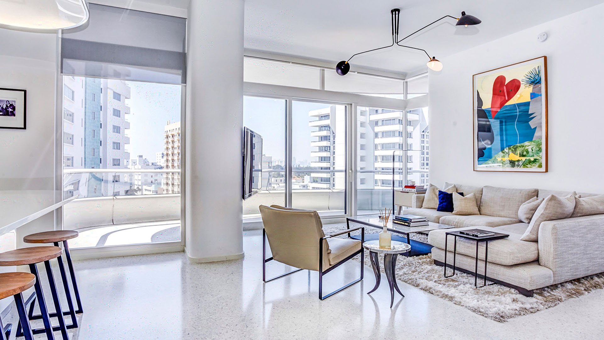 Corner living room at Faena House in Miami Beach, luxury and ultra luxury condos with a sectional sofa, balcony access, city views, bright white finishes, and modern seating.