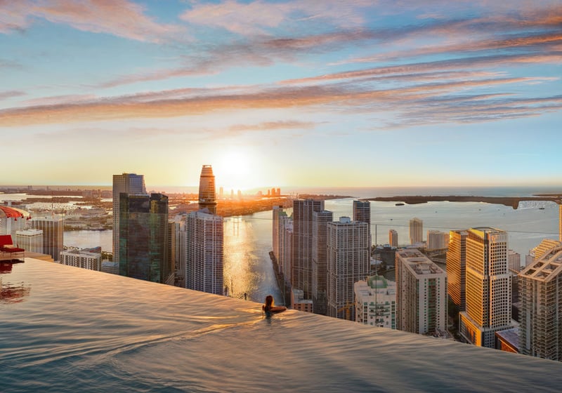 Faena Residences Miami rooftop infinity pool at sunrise with panoramic skyline and bay views, Downtown Miami. Luxury and ultra luxury preconstruction condos offering resort-level rooftop amenities and cabanas.