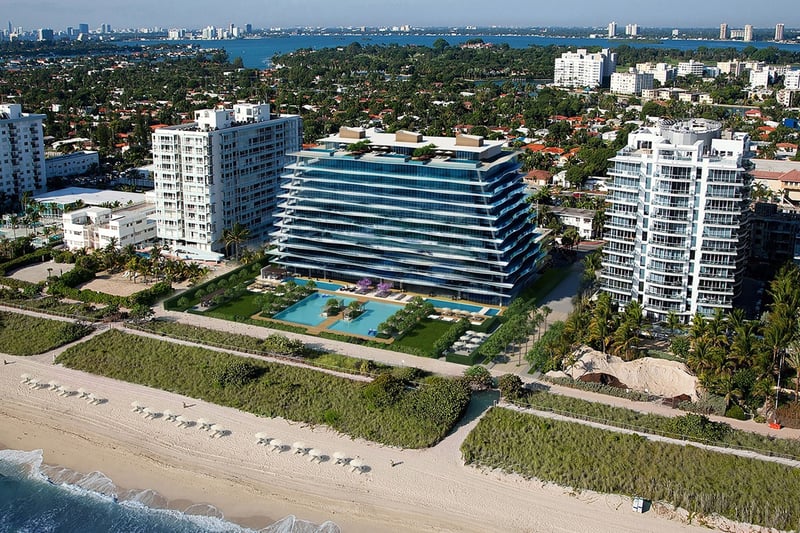 Aerial view of Fendi Chateau Residences in Surfside showing the beachfront tower, landscaped grounds, and pool terrace, showcasing luxury and ultra luxury condos along the shoreline.