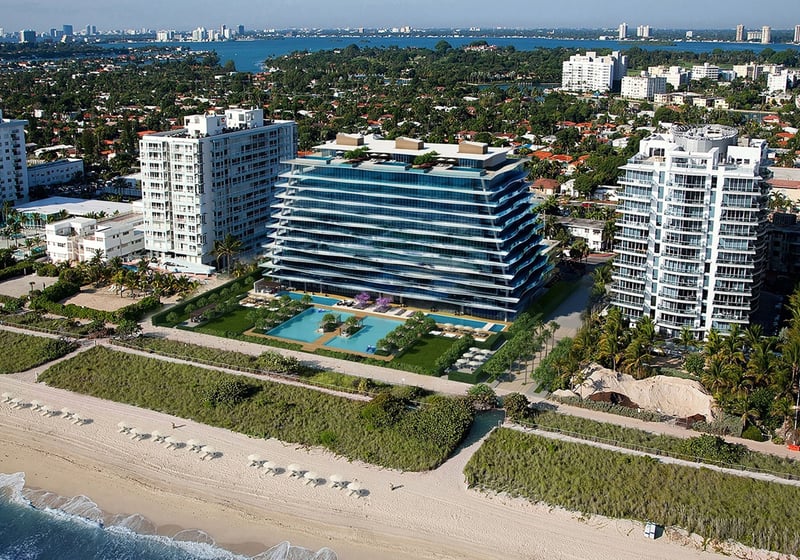 Aerial view of Fendi Chateau Residences in Surfside showing the beachfront tower, landscaped grounds, and pool terrace, showcasing luxury and ultra luxury condos along the shoreline.