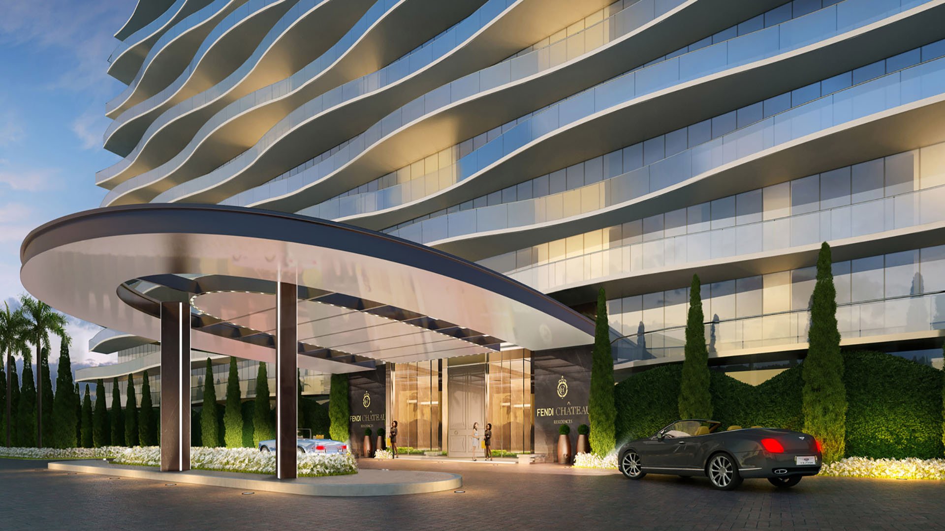 Angled dusk view of the porte cochere at Fendi Chateau Residences in Surfside with the curved facade, car arrival area, and elegant entry for luxury and ultra luxury condos.