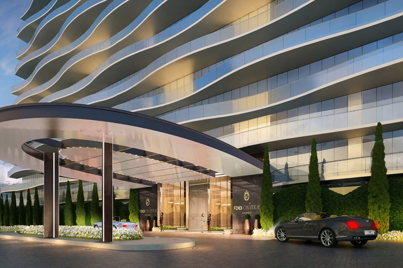 Angled dusk view of the porte cochere at Fendi Chateau Residences in Surfside with the curved facade, car arrival area, and elegant entry for luxury and ultra luxury condos.
