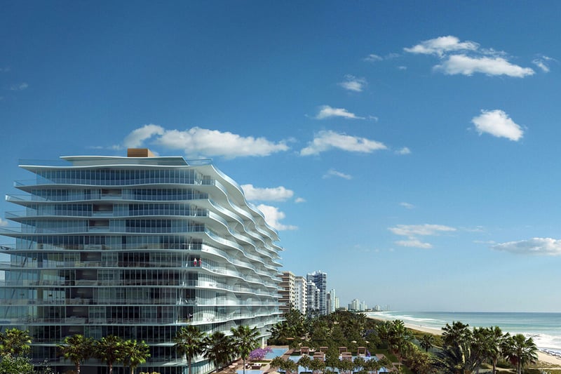 Side exterior view of Fendi Chateau Residences in Surfside with flowing balconies, palm trees, and a long beachfront skyline, highlighting luxury and ultra luxury condos by the ocean.