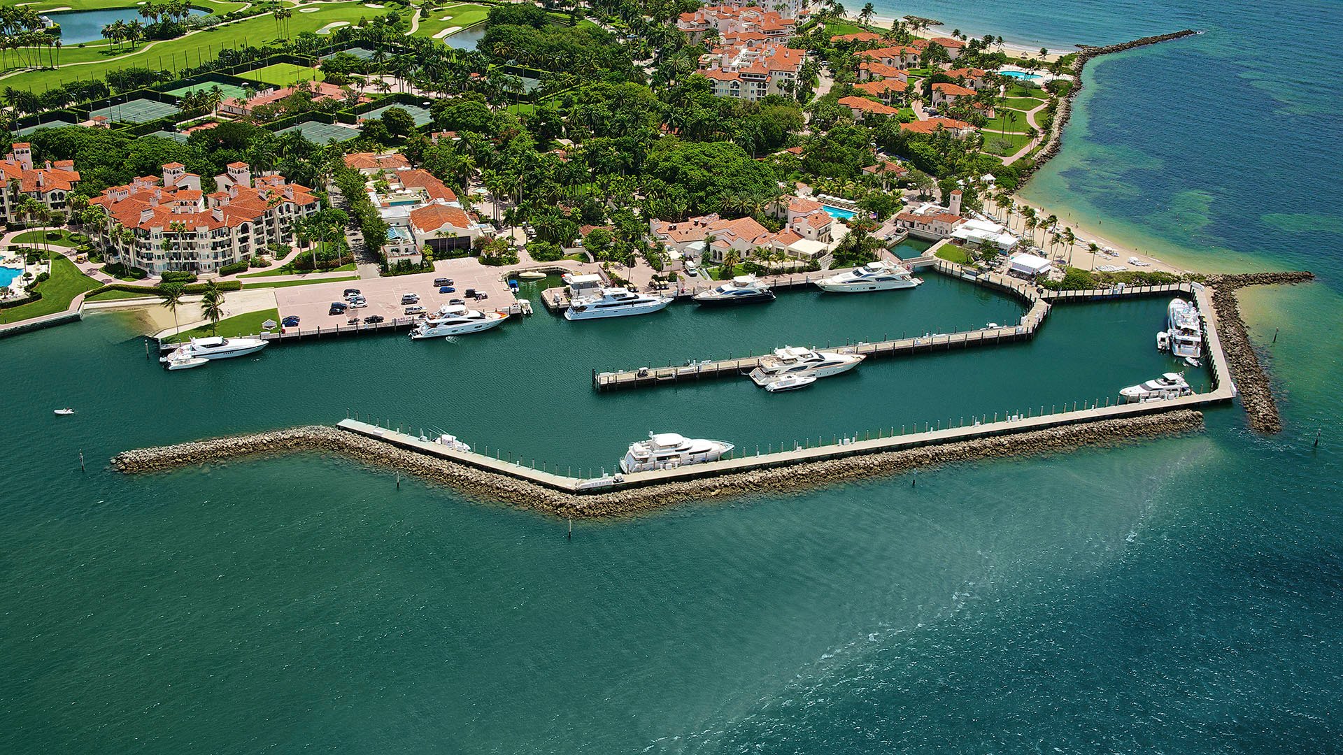 Fisher Island luxury and ultra luxury condos amenity with an aerial deep dockage marina, yachts, shoreline residences, and a sandy beach.