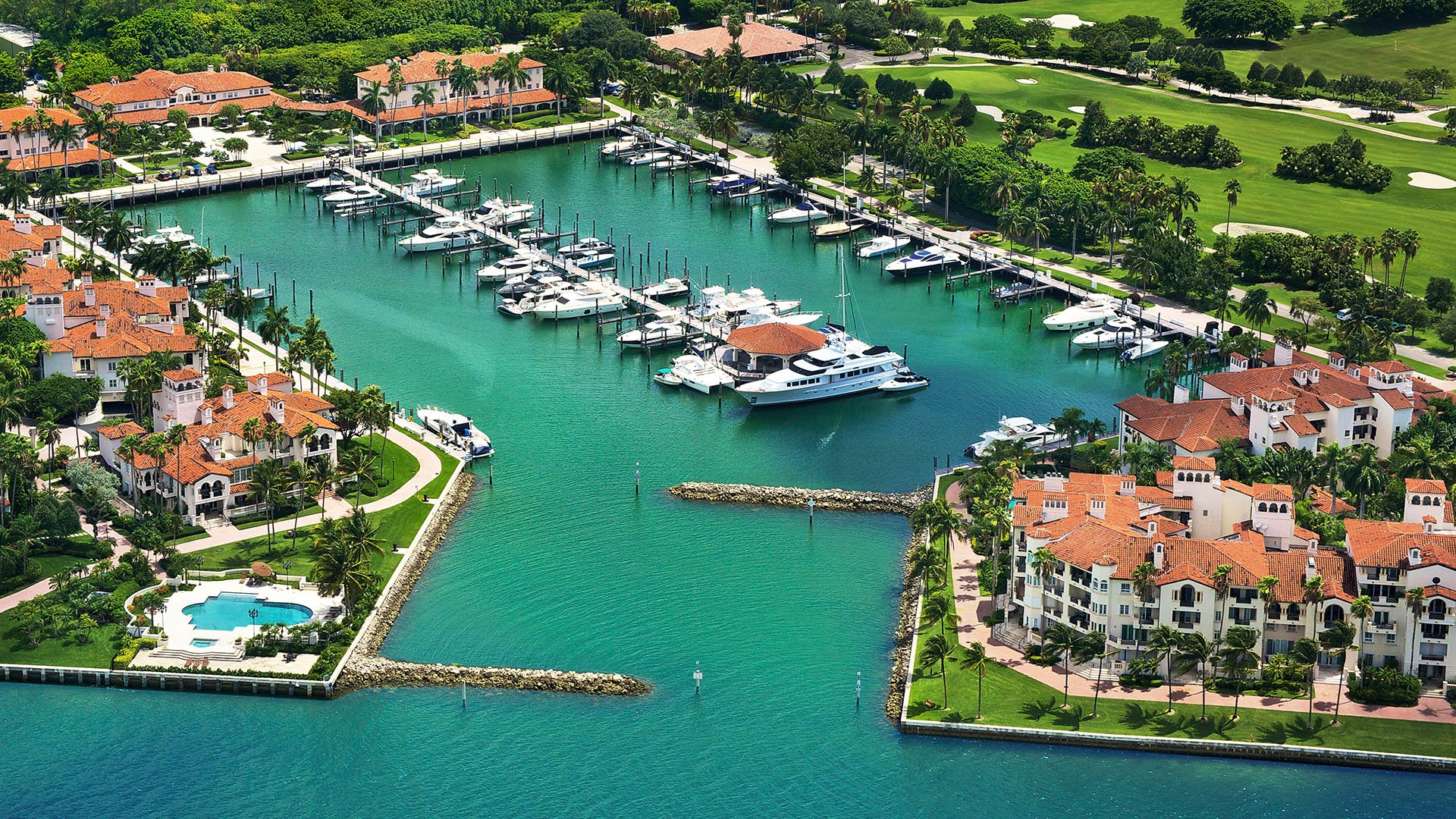 Fisher Island luxury and ultra luxury condos amenity with an aerial resident marina lined with private yacht slips and waterfront buildings.