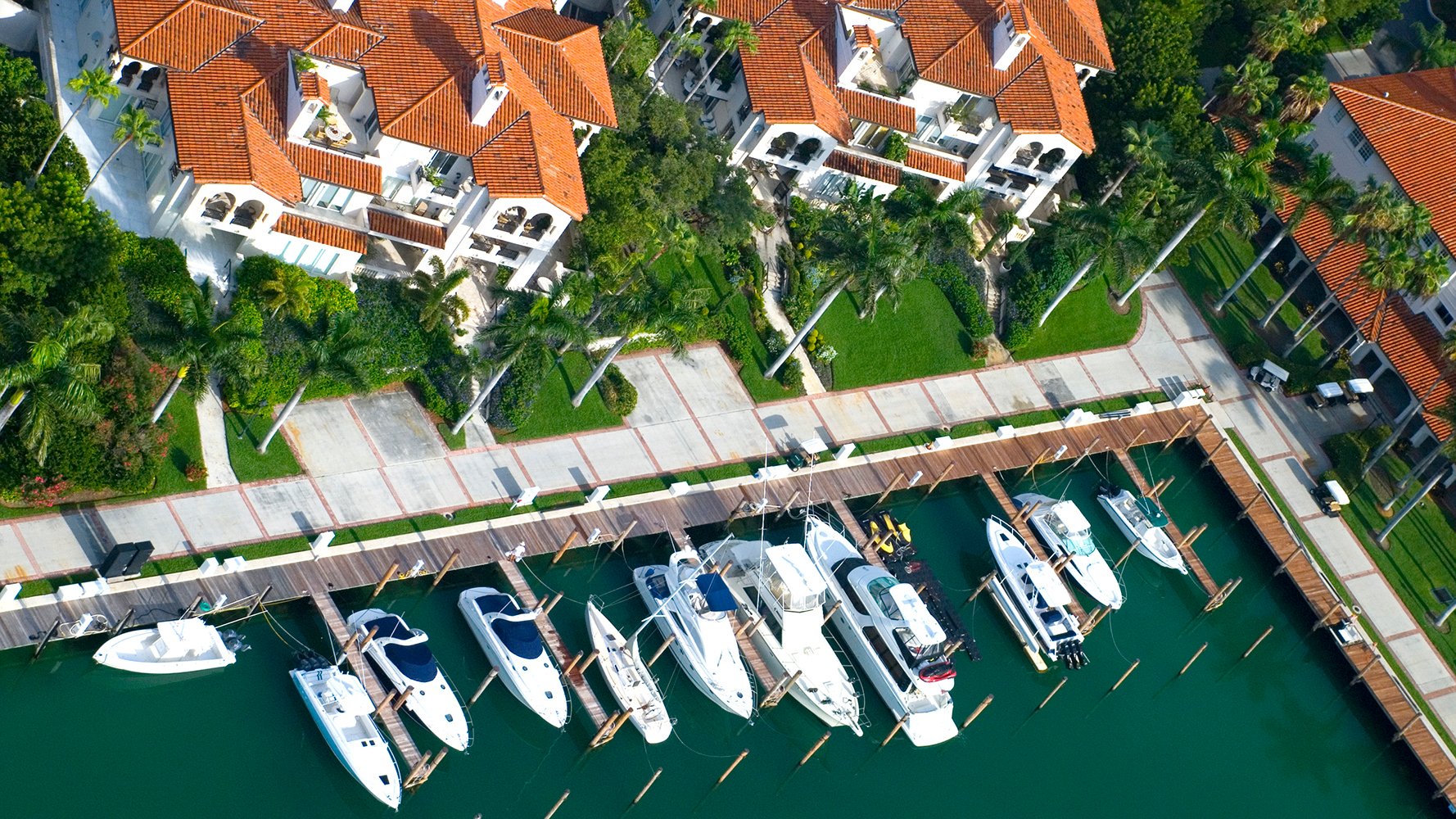 Fisher Island, Miami coastal marina aerial with yachts and Mediterranean‑style condos, exclusive private‑island enclave of luxury and ultra luxury condos; strong resale market. Featuring view.