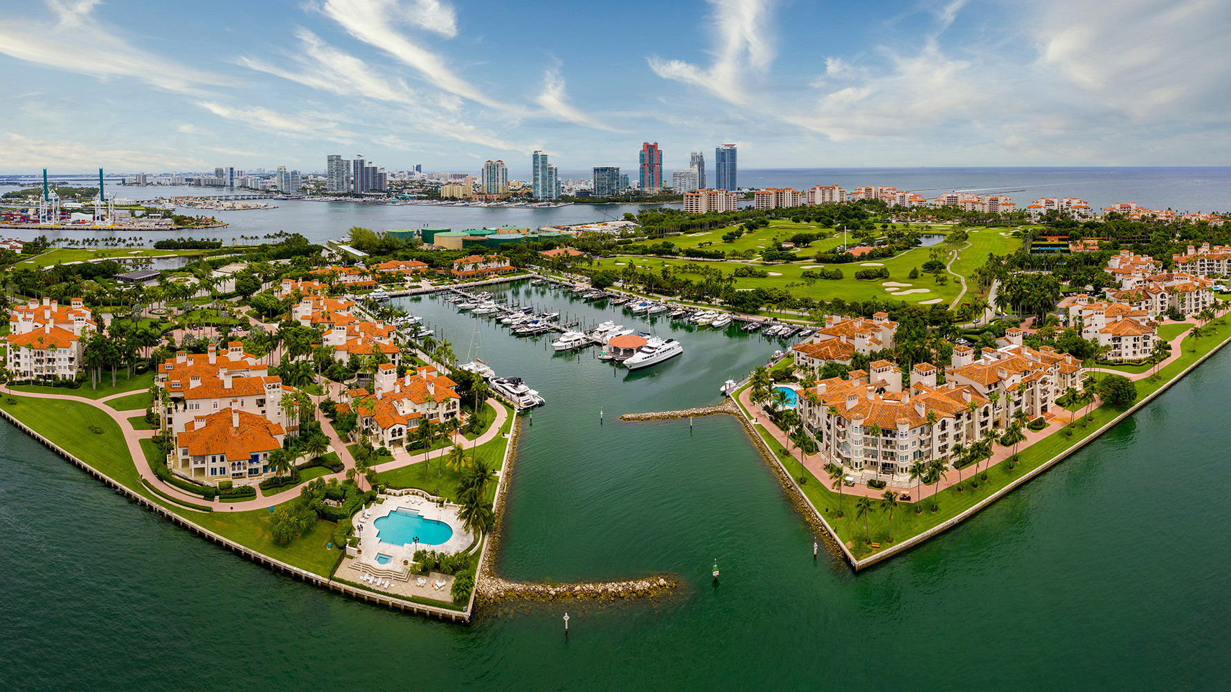 Fisher Island, Miami marina framed by skyline and resort architecture, secluded setting of luxury and ultra luxury condos; premier resale opportunities. Featuring coastal and cityscape.