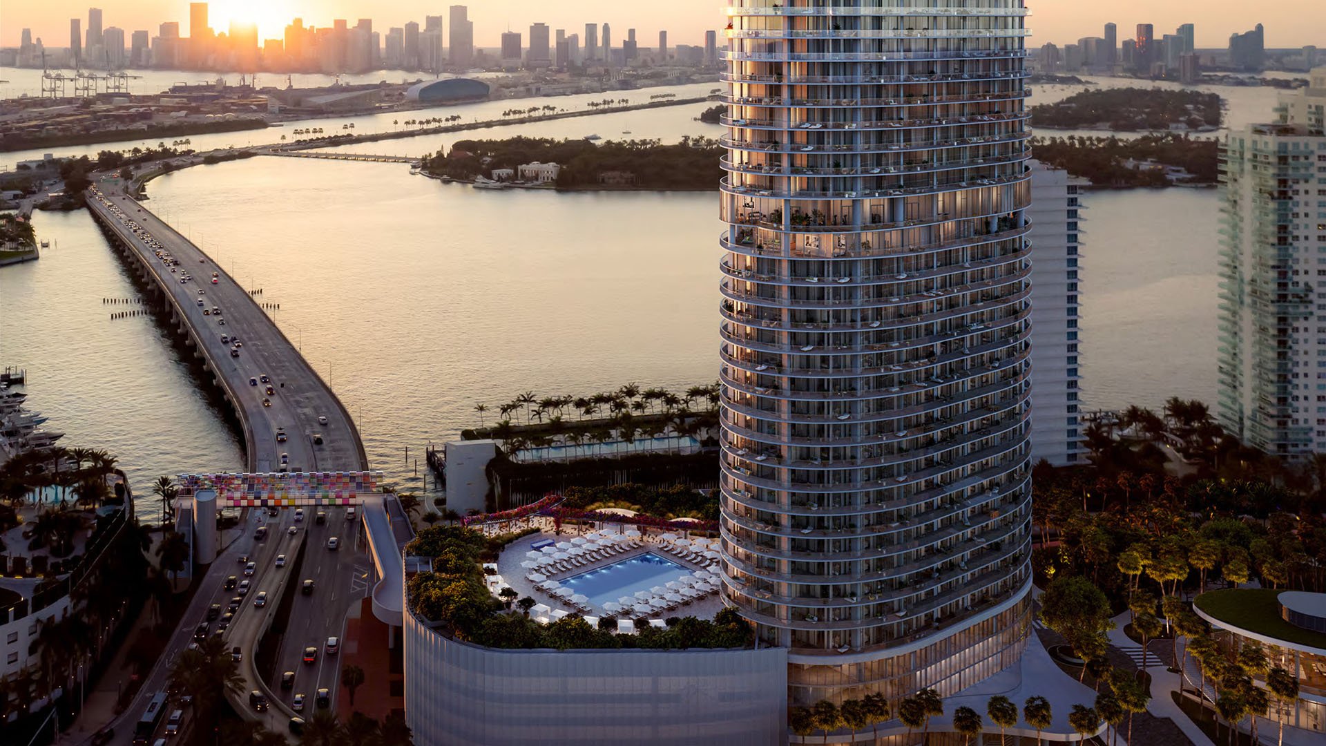 Aerial waterfront view of the tower, bridge and amenity deck at Five Park in Miami Beach, luxury and ultra luxury condos at sunset.