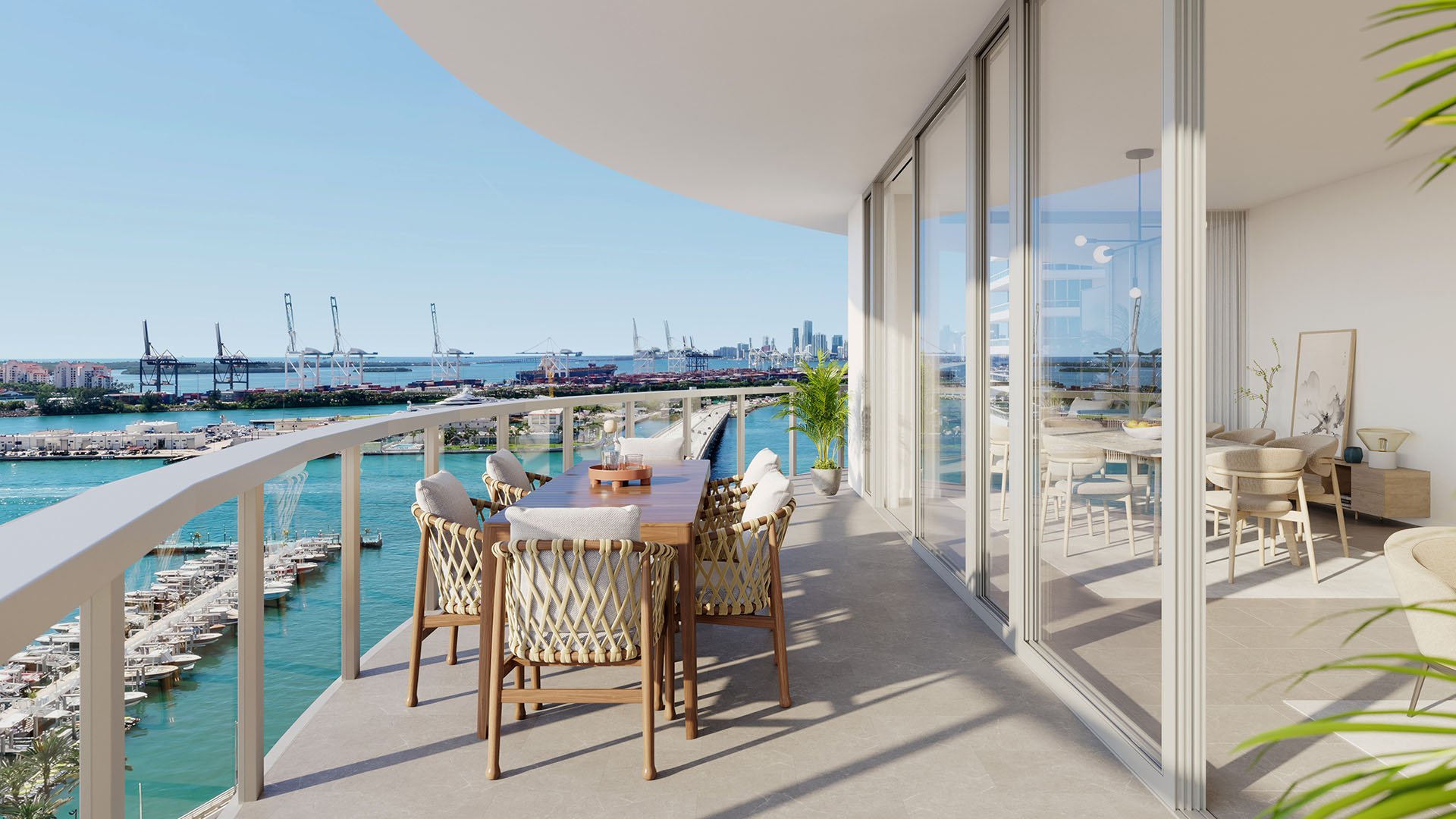Curved balcony dining area overlooking a marina and bay view at Five Park in Miami Beach, luxury and ultra luxury condos with floor to ceiling glass and outdoor seating.
