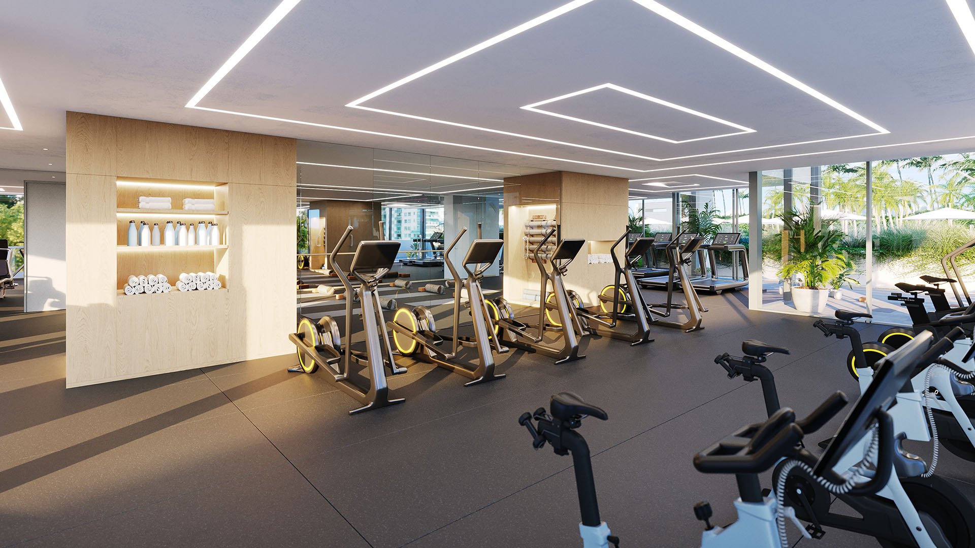 Fitness center at Five Park in Miami Beach, luxury and ultra luxury condos with cardio machines, geometric ceiling lighting and greenery beyond the windows.