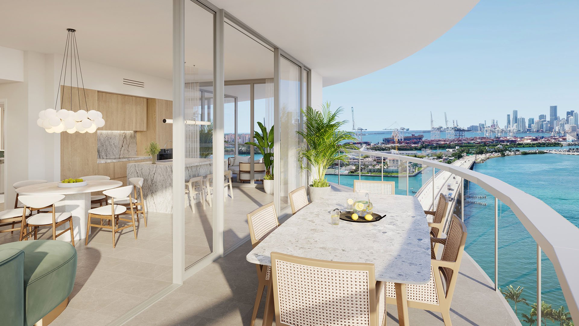 Wraparound balcony with marble dining table and bay skyline view at Five Park in Miami Beach, luxury and ultra luxury condos connected to an open kitchen and living area.