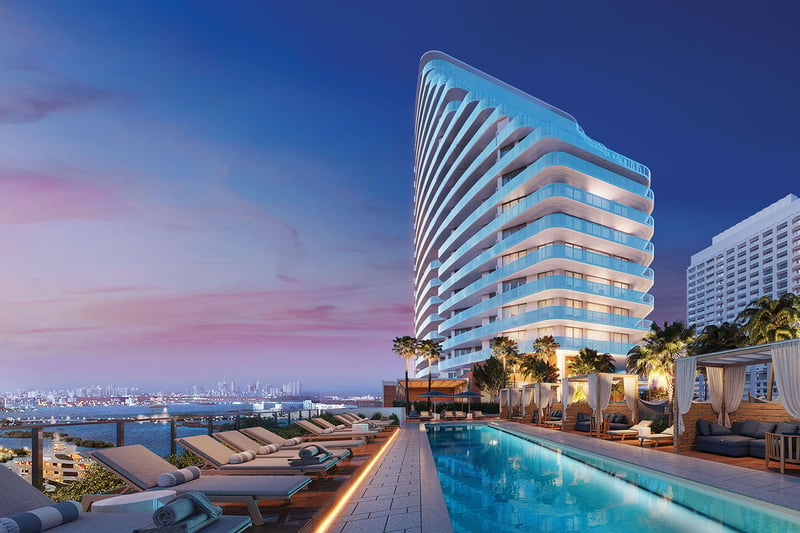 Curved tower exterior beside a long pool, cabanas, and twilight skyline views at Four Seasons Residences Fort Lauderdale in Fort Lauderdale, highlighting luxury and ultra luxury condos with signature waterfront design.