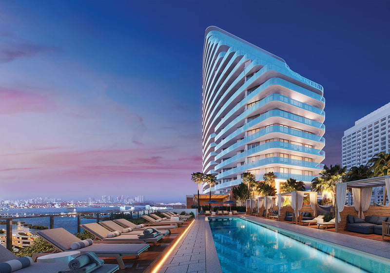 Curved tower exterior beside a long pool, cabanas, and twilight skyline views at Four Seasons Residences Fort Lauderdale in Fort Lauderdale, highlighting luxury and ultra luxury condos with signature waterfront design.