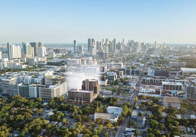 Aerial neighborhood view of Frida Kahlo Residences in Wynwood, showing luxury and ultra luxury condos with the project in the foreground and the downtown Miami skyline and bay beyond.