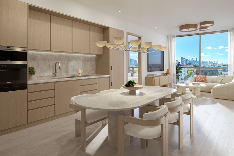 Chef kitchen and dining area at Frida Kahlo Residences in Wynwood, showcasing luxury and ultra luxury condos with light wood cabinetry, stone surfaces, and a bright skyline view through large windows.