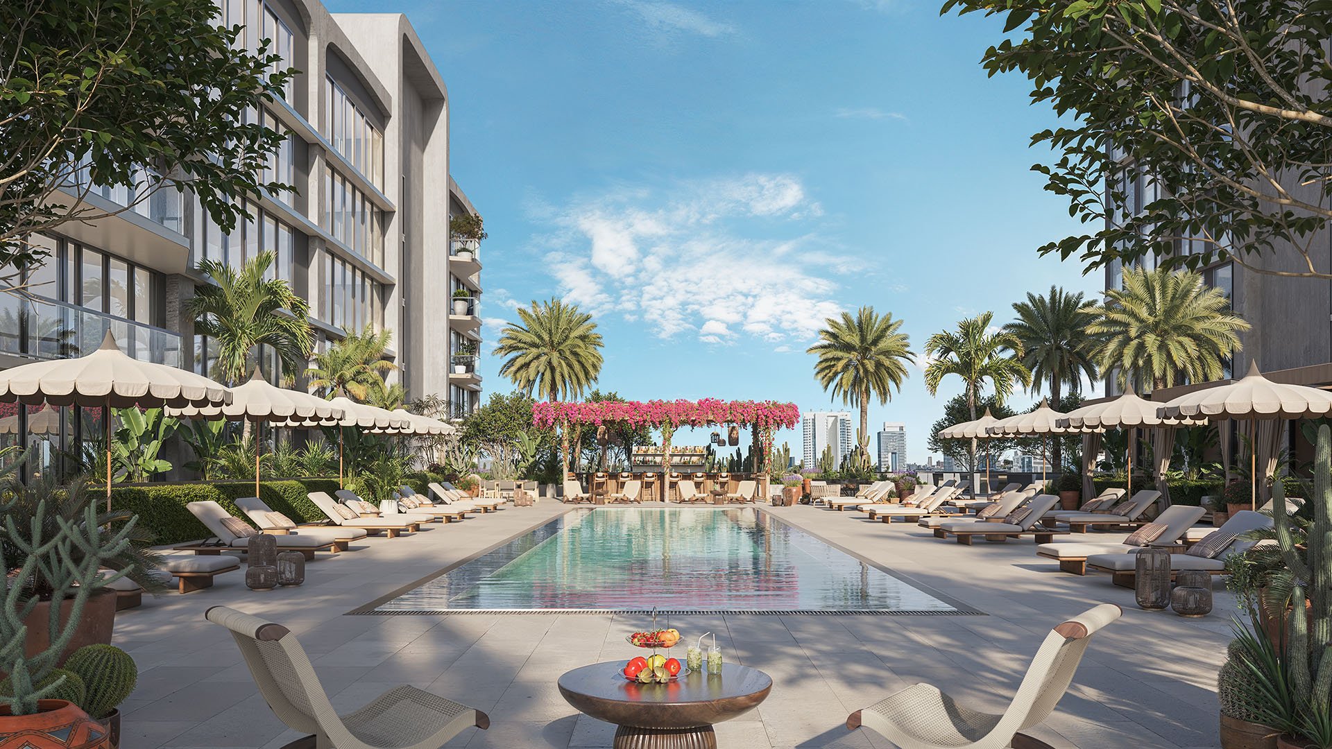 Resort-style pool terrace at Frida Kahlo Residences in Wynwood, created for luxury and ultra luxury condos living with palm trees, sun loungers, umbrellas, and a flower-covered pergola lounge.