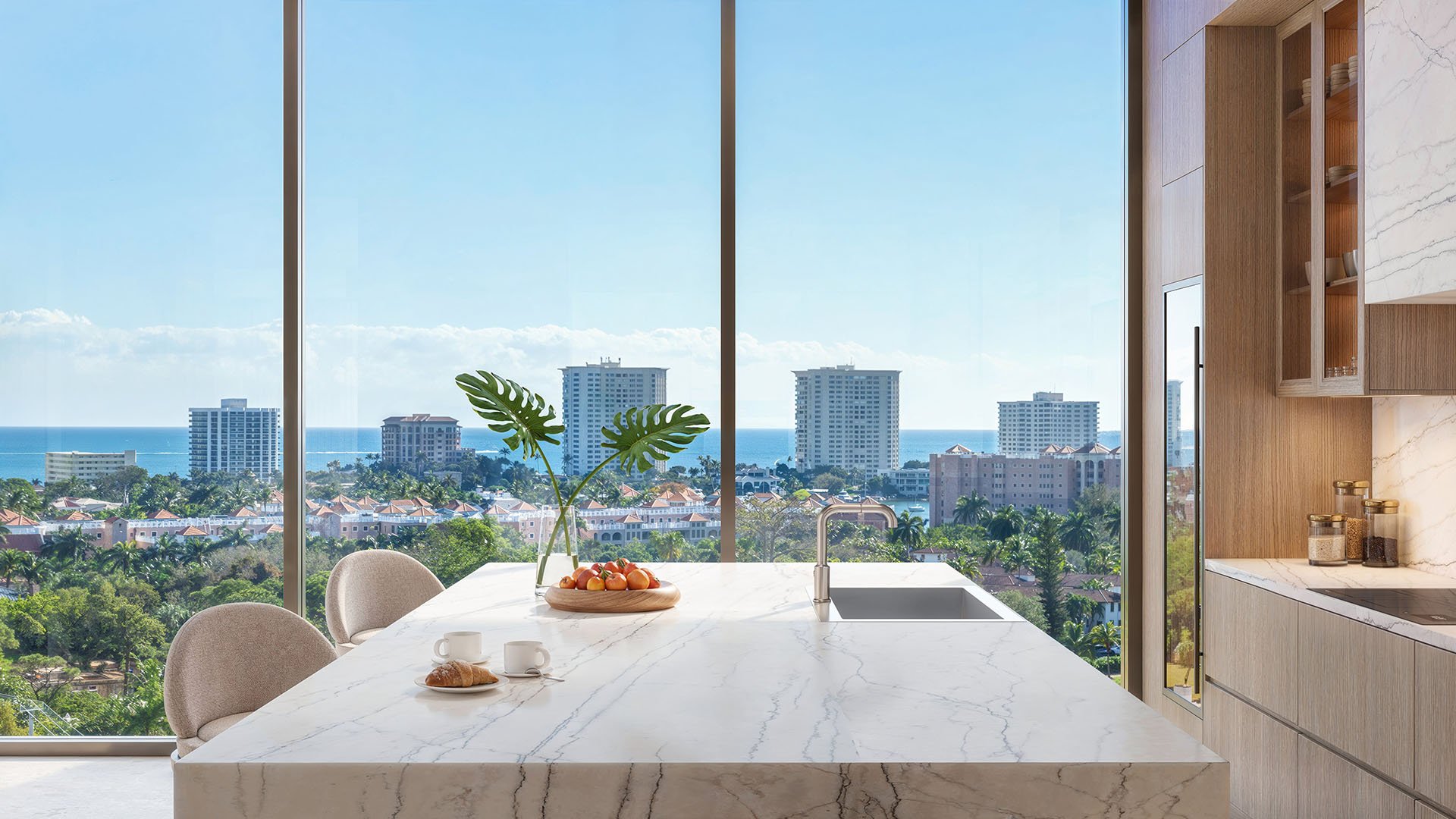 Glass House Boca Raton luxury kitchen with marble island, sink and floor-to-ceiling windows framing ocean view, highlighting ultra luxury preconstruction condos residences in Boca Raton, Florida.