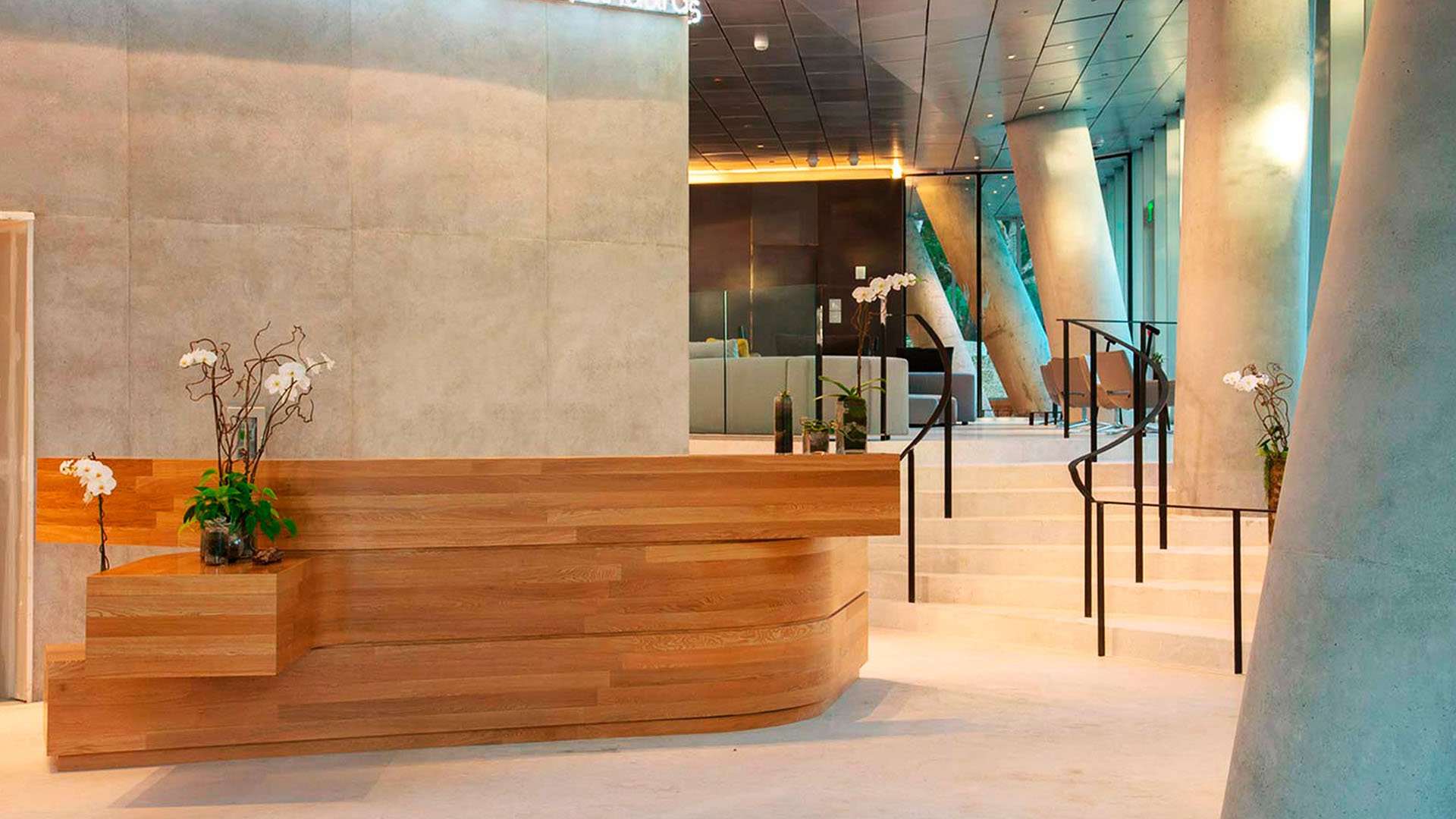Grove at Grand Bay, Coconut Grove luxury and ultra luxury condos with a concierge lobby featuring a curved wood reception desk, sculptural columns, and a sweeping staircase.