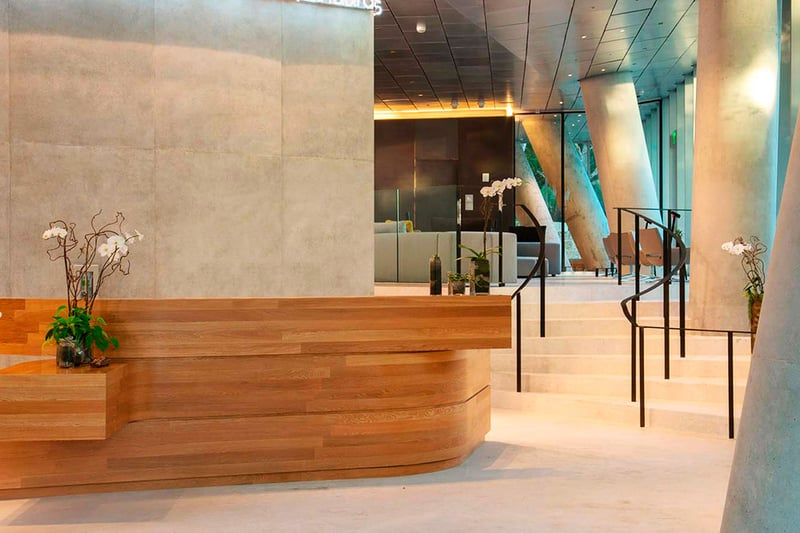Grove at Grand Bay, Coconut Grove luxury and ultra luxury condos with a concierge lobby featuring a curved wood reception desk, sculptural columns, and a sweeping staircase.