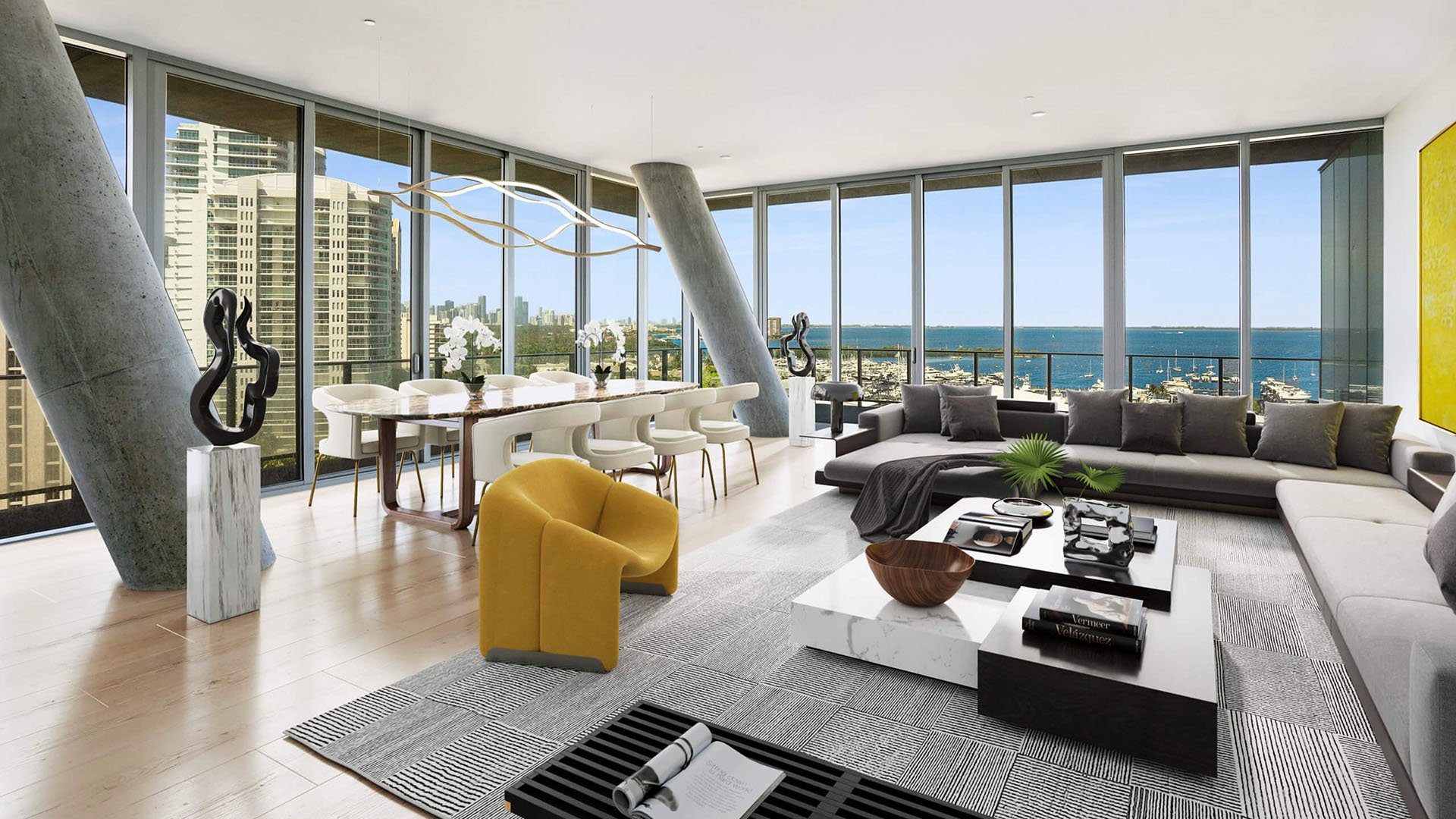 Grove at Grand Bay, Coconut Grove luxury and ultra luxury condos with an open living and dining room, gray sectional sofa, yellow chair, and sweeping marina views.
