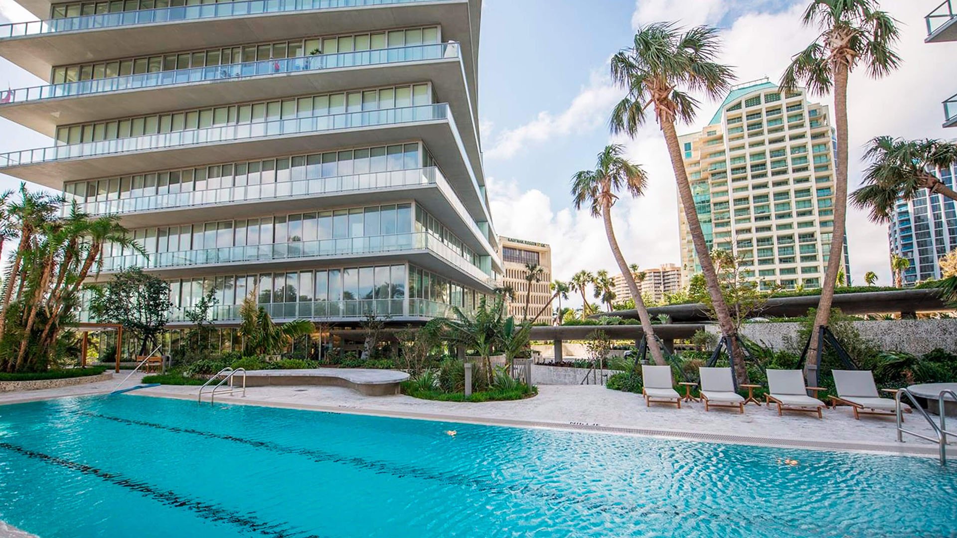 Grove at Grand Bay, Coconut Grove luxury and ultra luxury condos with a resort-style pool deck, palm landscaping, chaise loungers, and the tower facade rising above.