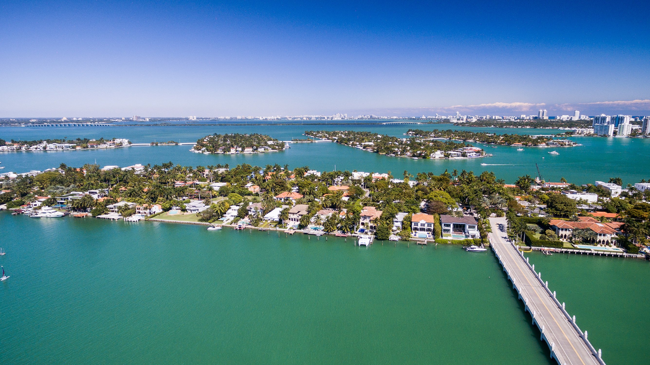 Aerial of Palm, Hibiscus and Star Islands, Miami—curving canals and waterfront homes; prestigious zone with luxury and ultra luxury condos, active resale.