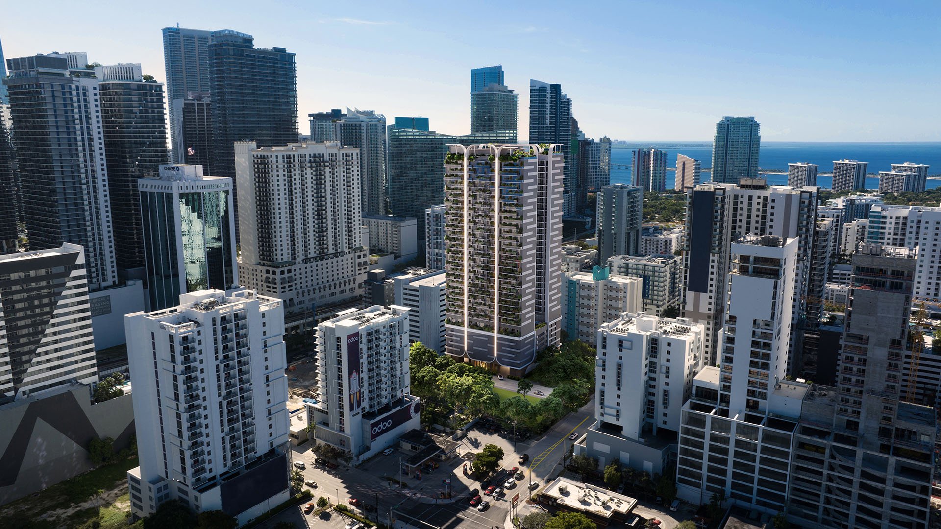 Aerial view of the House of Wellness in Brickell preconstruction luxury and ultra luxury condos tower rising among the skyline with a bay horizon in the distance.