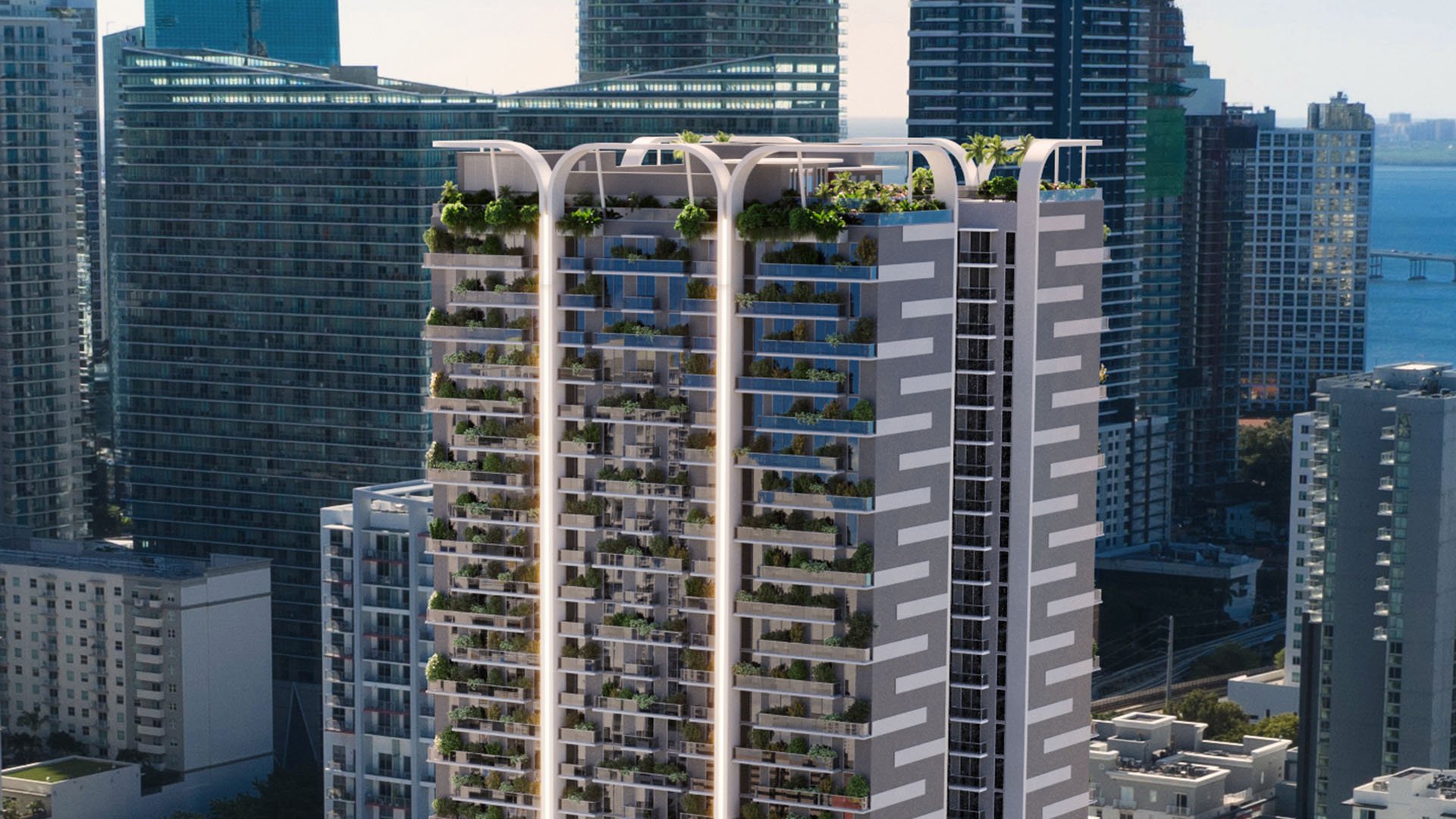 Oblique exterior view of House of Wellness in Brickell preconstruction luxury and ultra luxury condos showing planted balconies, the rooftop crown, and nearby waterfront towers.